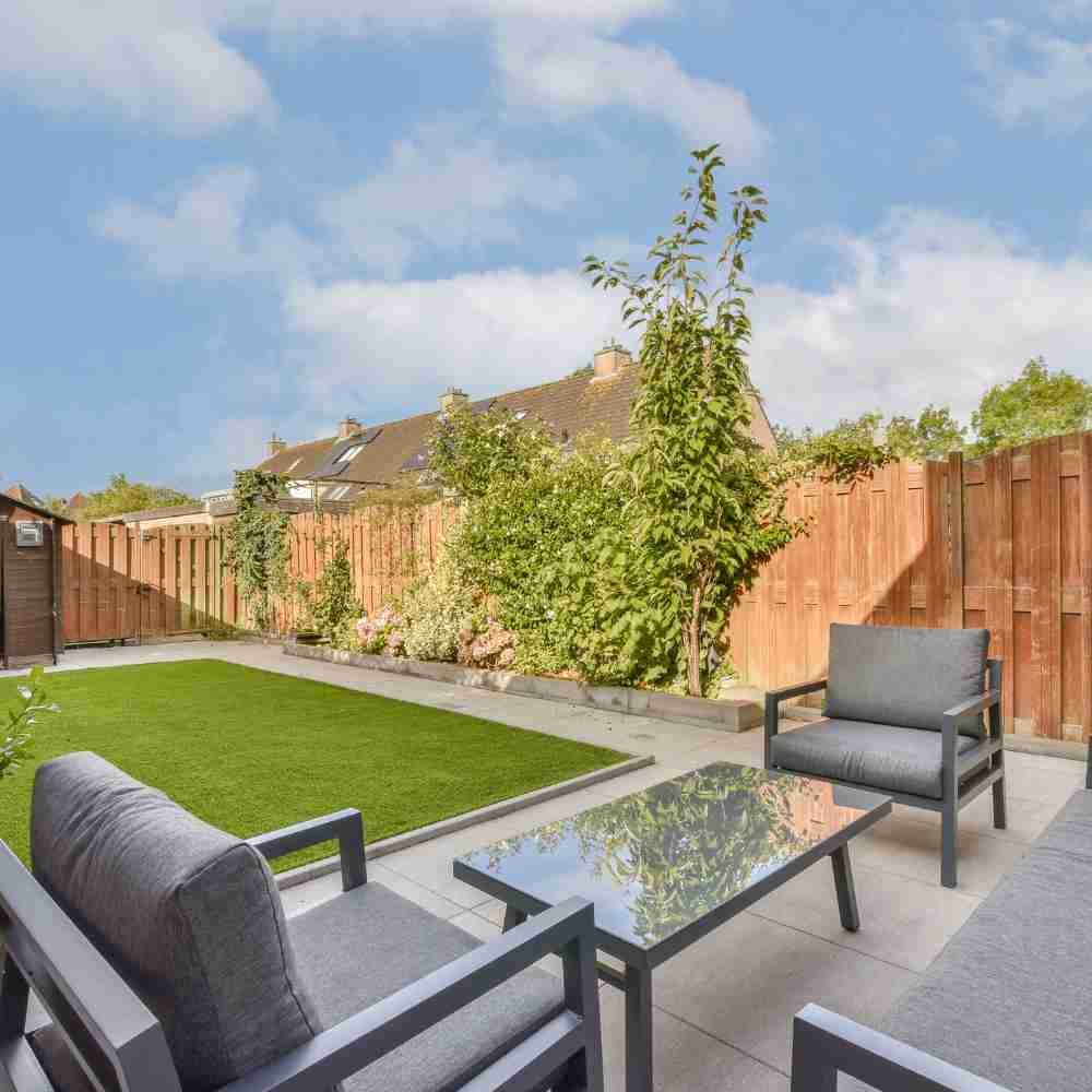 Illustrative modern garden patio with seating, lawn and planted borders